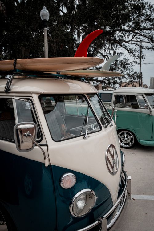 Free Classic Volkswagen minibus with surfboards on roof in a sunny outdoor parking lot. Stock Photo