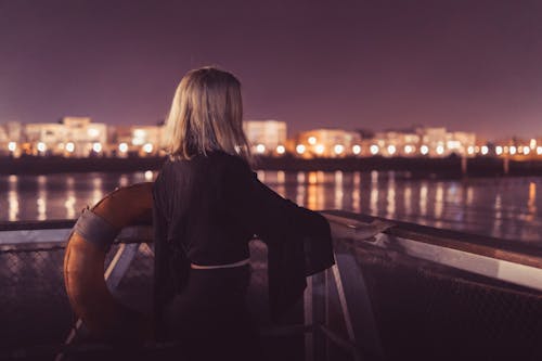 Woman Standing Near Body of Water during Night Time