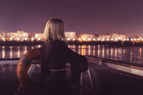 Frau, Die Nahe Körper Des Wassers Während Der Nachtzeit Steht