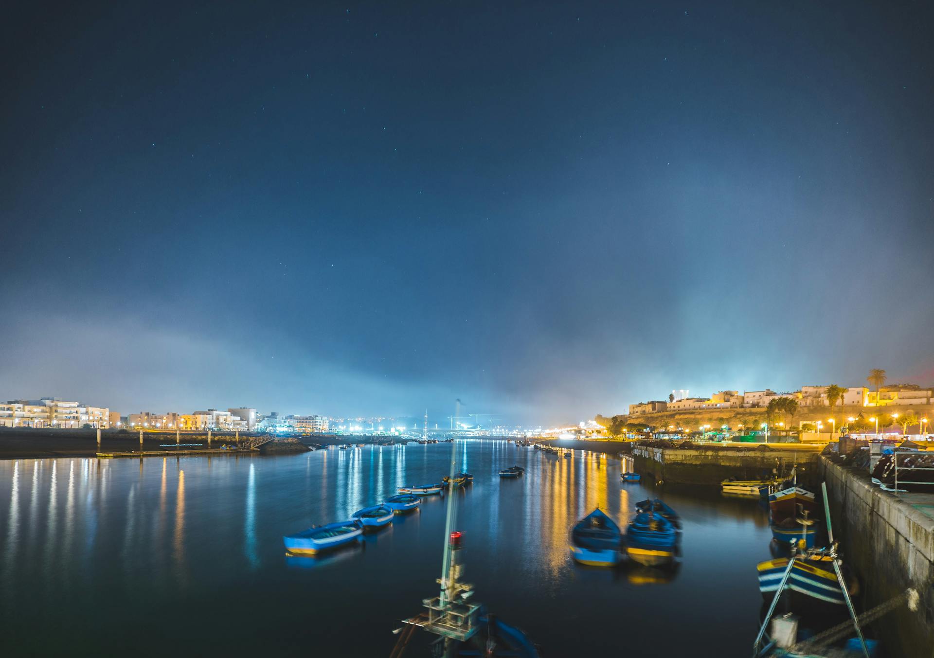 Long exposure of illuminated Salé waterfront with boats and reflections.