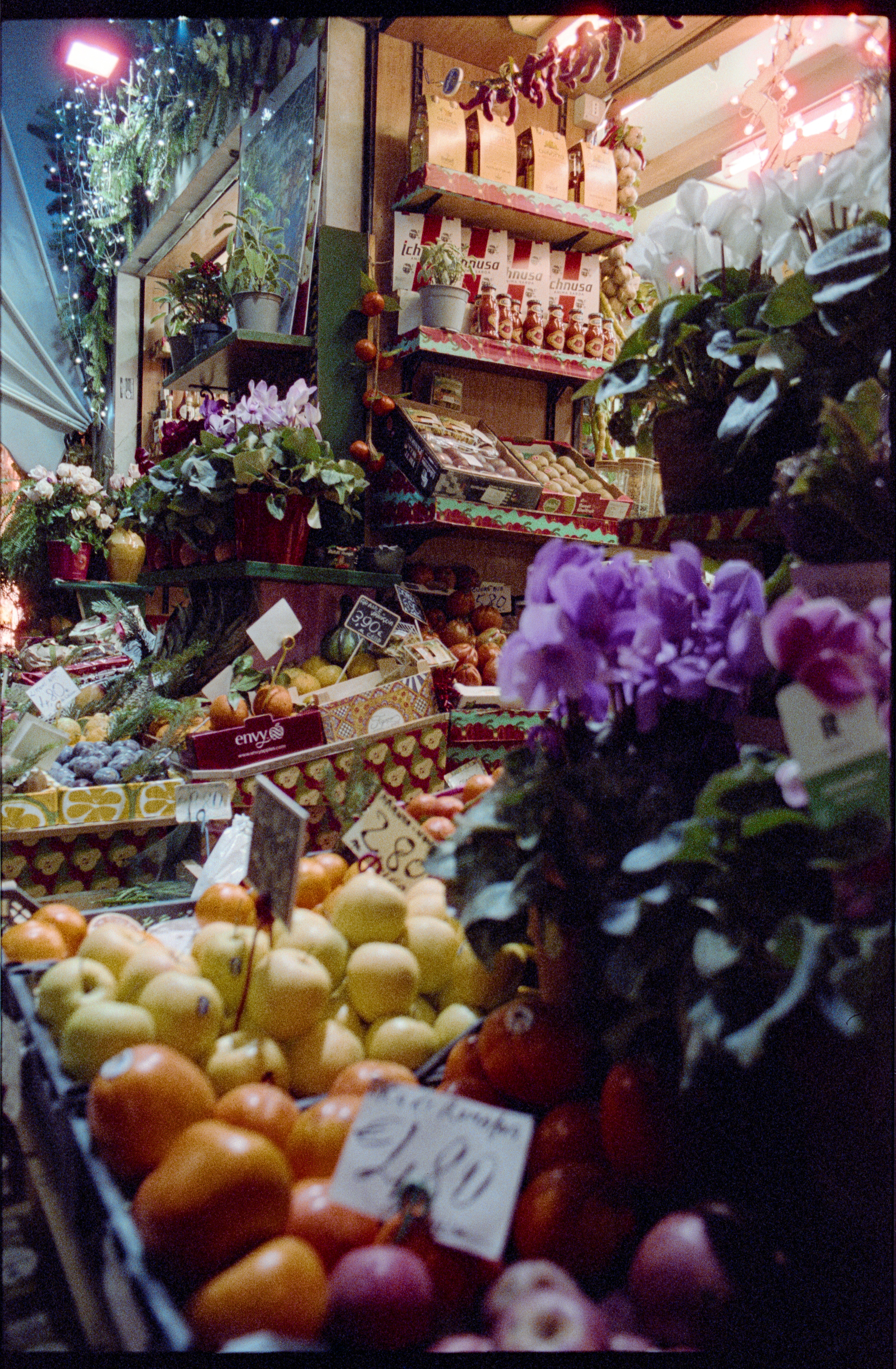A bustling market stall showcasing fresh fruits, flowers, and holiday decorations in Milan, Italy.