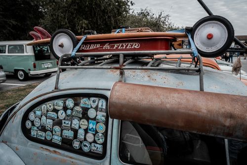 Free A rusted vintage Volkswagen car adorned with travel stickers and surfboards, showcasing nostalgic charm. Stock Photo