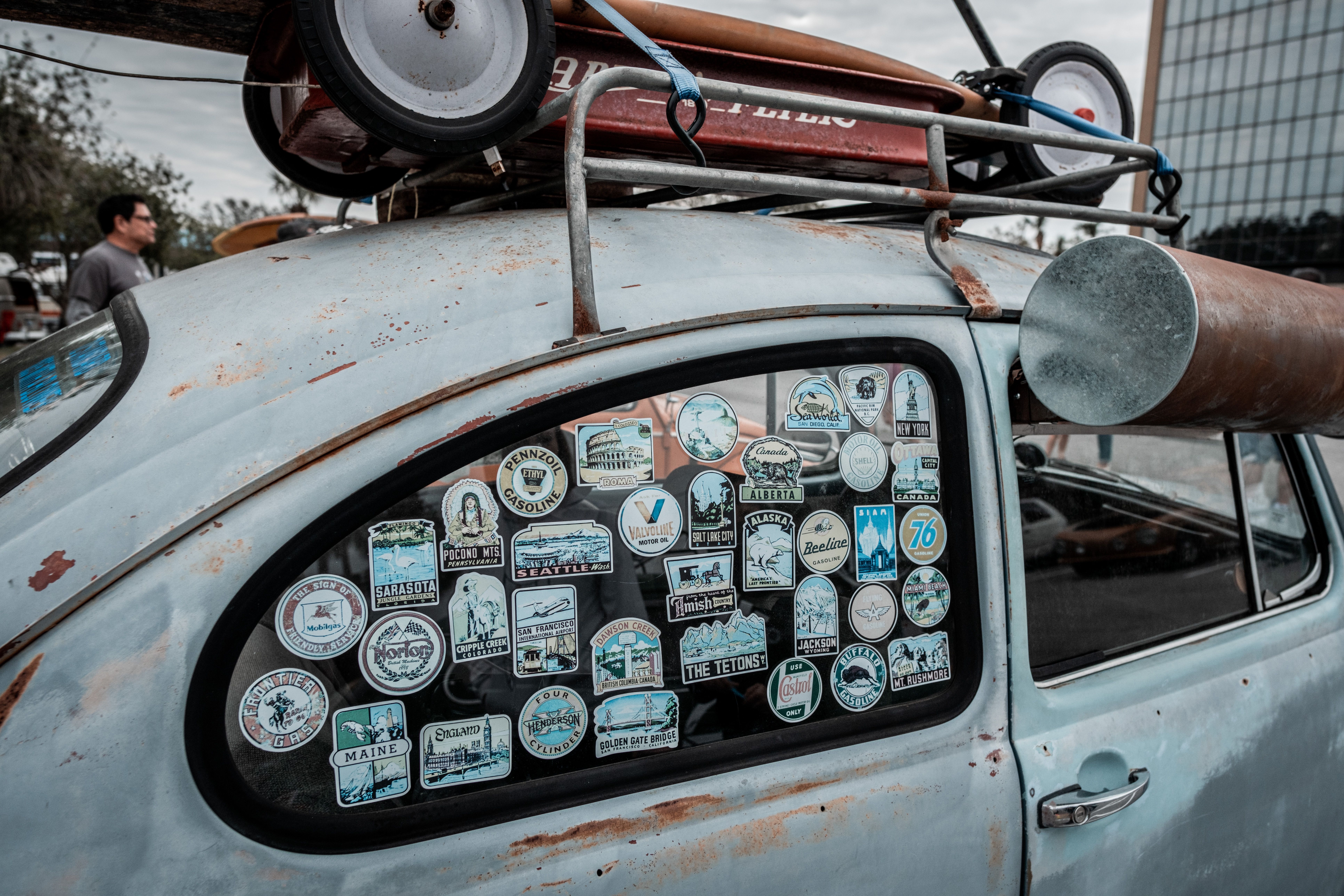 Close-up of vintage car window covered in various travel stickers, showcasing retro vibes.