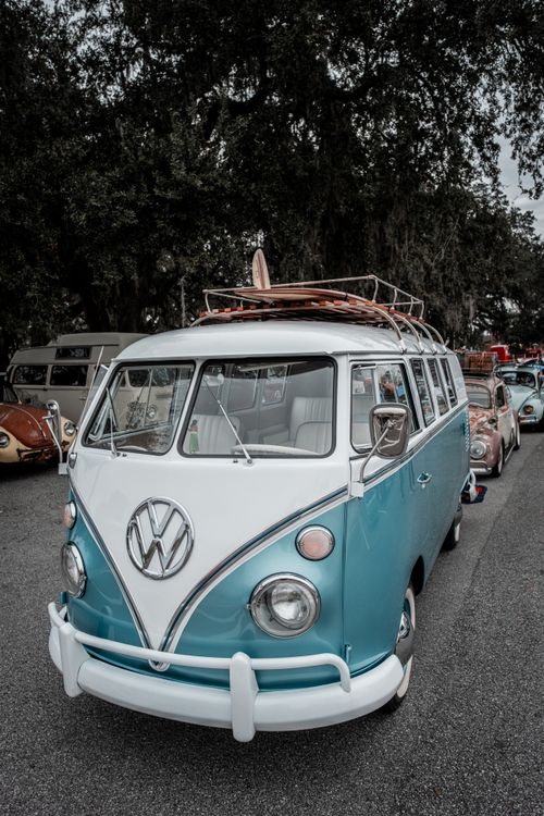 Free Classic blue and white vintage Volkswagen bus parked with a surfboard on top. Stock Photo