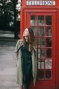 Photograph of a Woman Standing in Front of a Telephone Booth