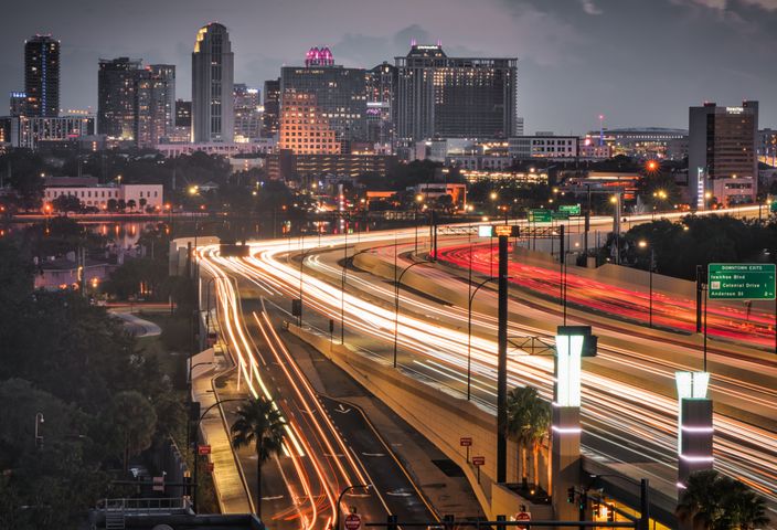 Stunning aerial view of Orlando skyline at dusk, showcasing vibrant light trails and bustling city life.