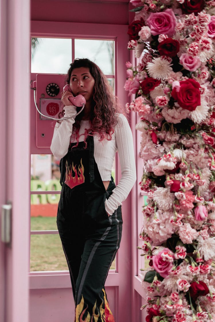 Woman Talking In Phone Booth With Flowers Decoration