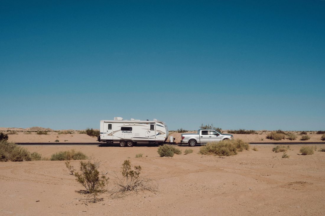 A camper trailer towed by a truck across remote desert — photo by Alfo Medeiros on Pexels