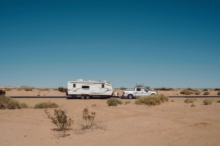 RV With Caravan On Road Through Desert