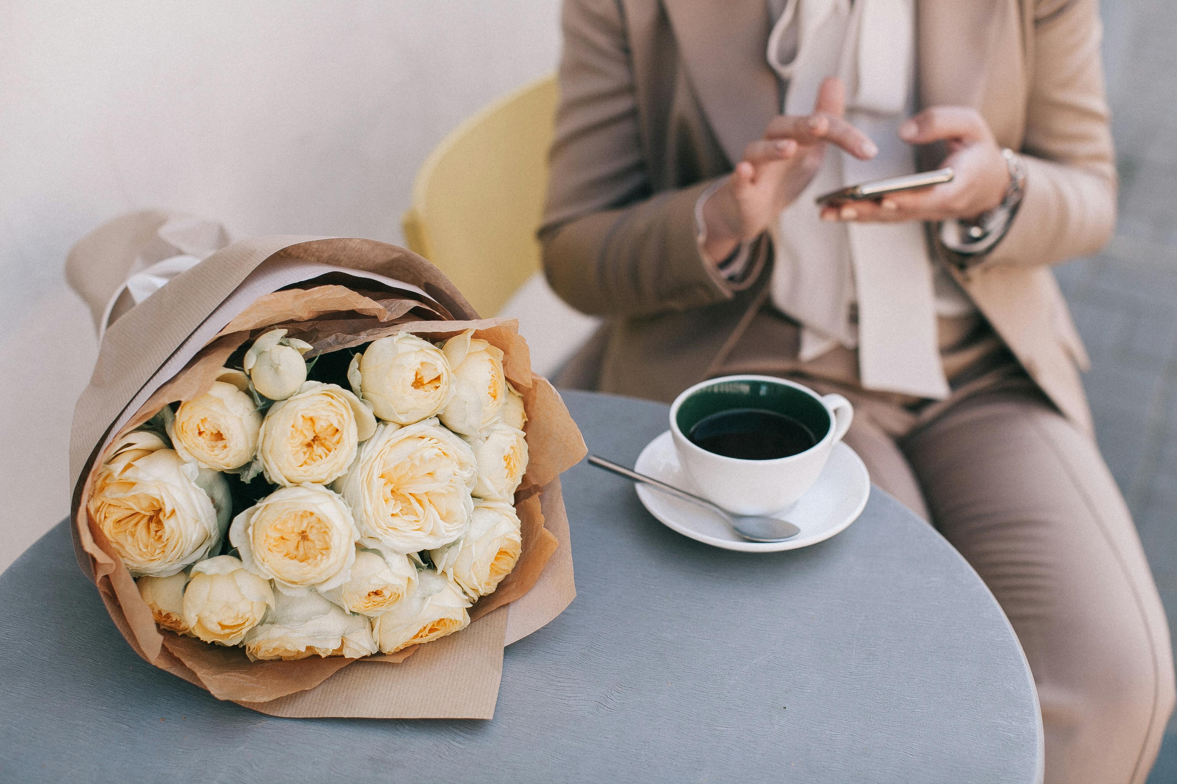 bouquet of white roses beside cup of tea