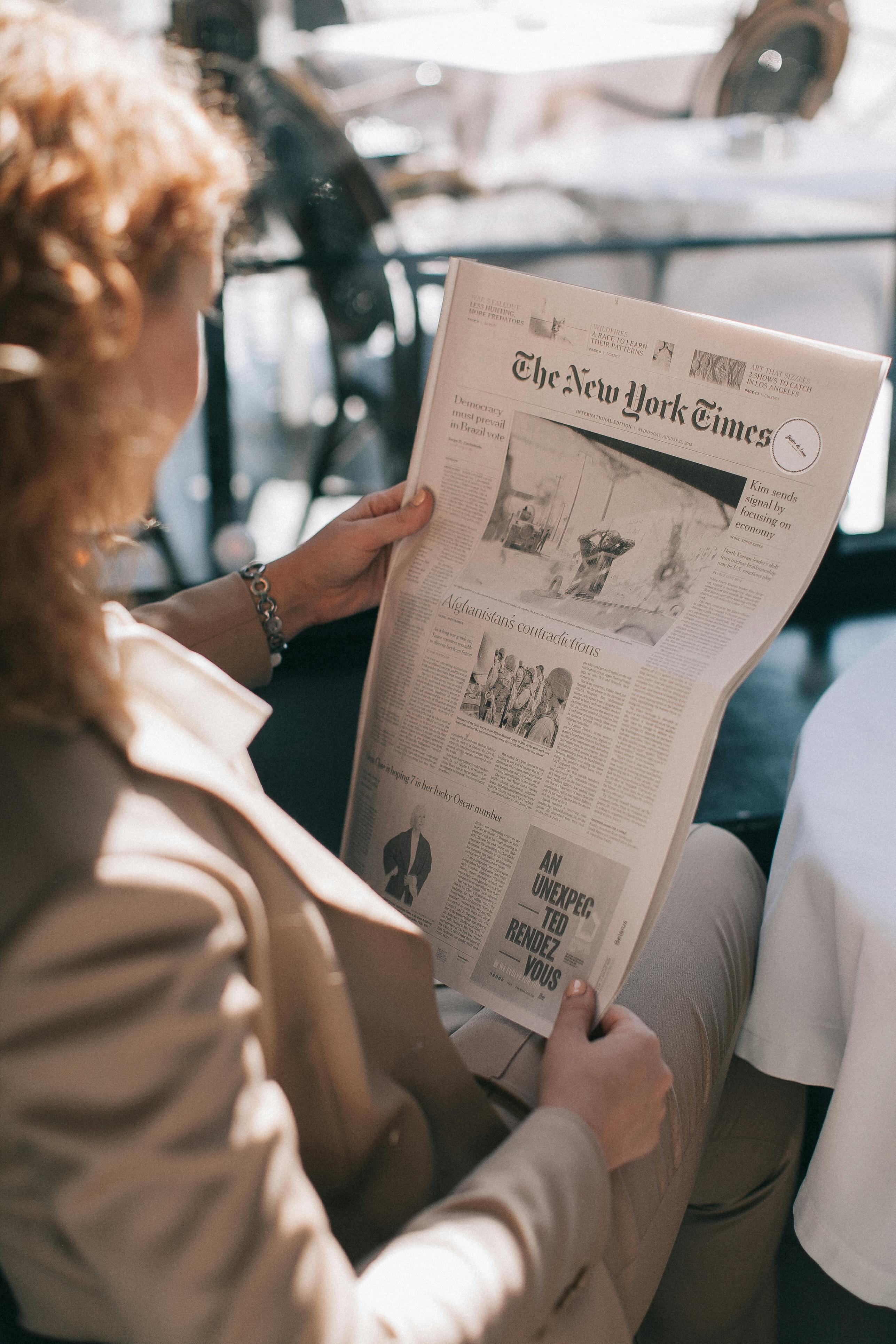 woman holding the new york times newspaper