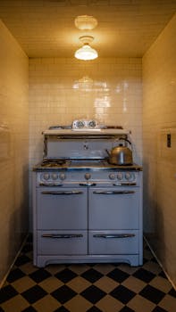 Old-fashioned stove with kettle in a well-lit tiled kitchen corner.