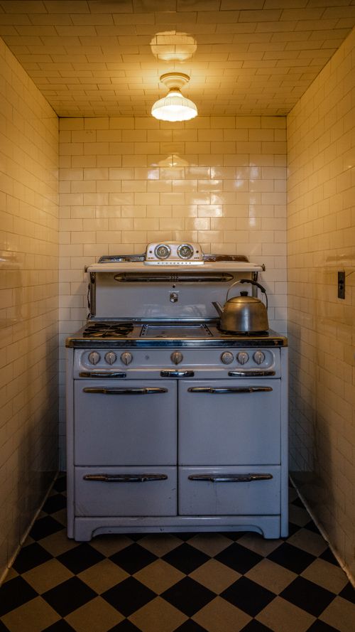 Free Old-fashioned stove with kettle in a well-lit tiled kitchen corner. Stock Photo