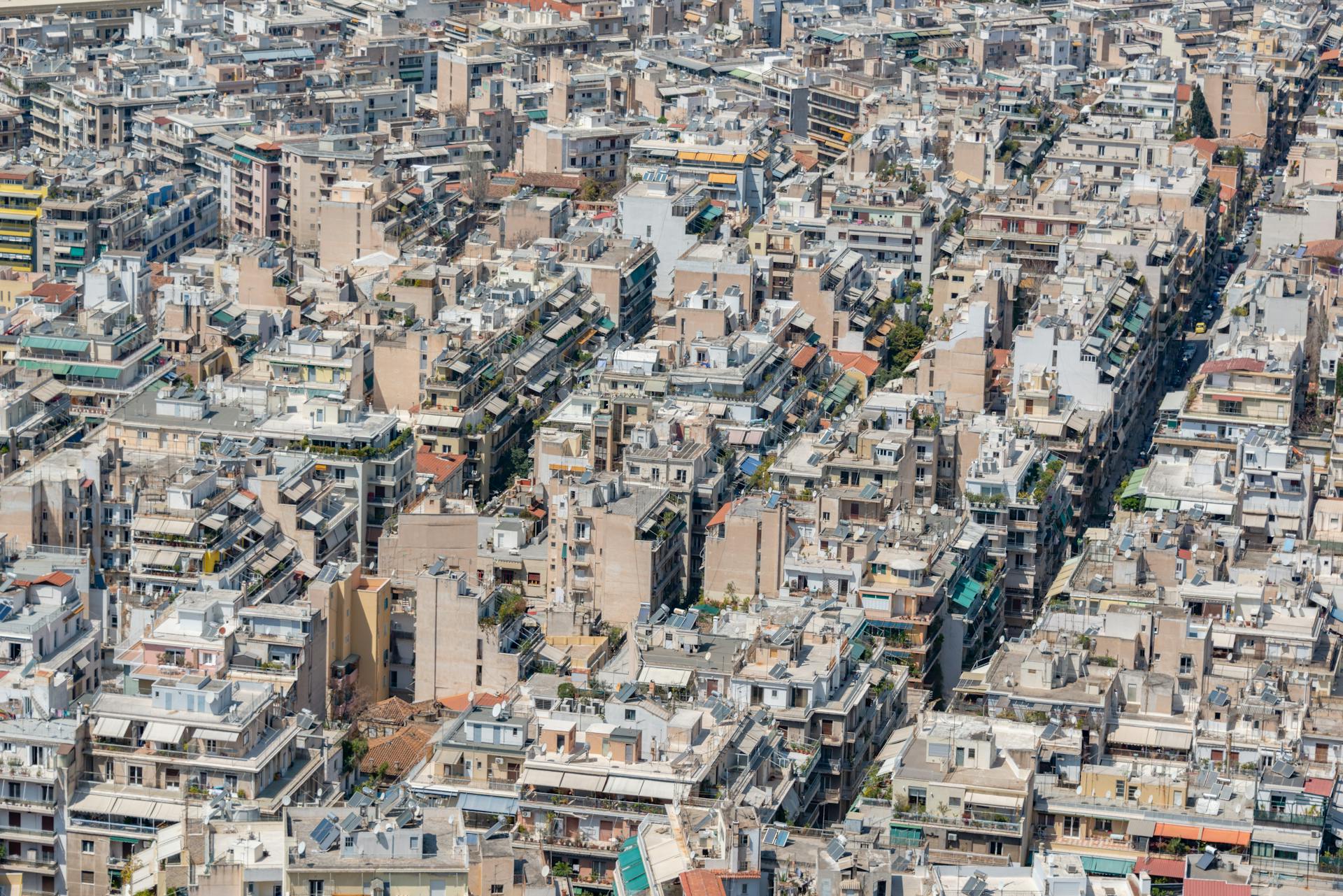 Panoramic aerial shot of densely packed residential buildings in Athens, Greece during daytime.