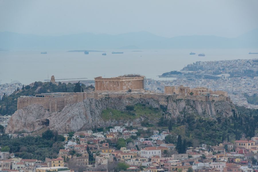 The Acropolis and the Parthenon on the hill above the Athens cityscape with the sea in the distance