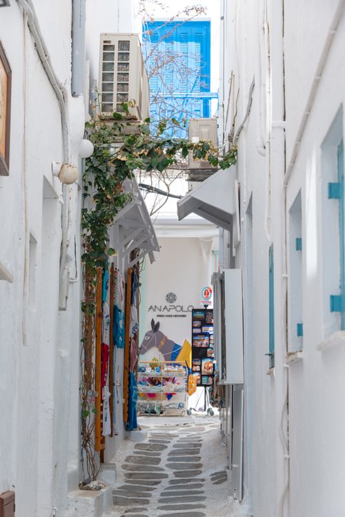 Free Explore a picturesque narrow alleyway with traditional white buildings on a Greek island. Stock Photo