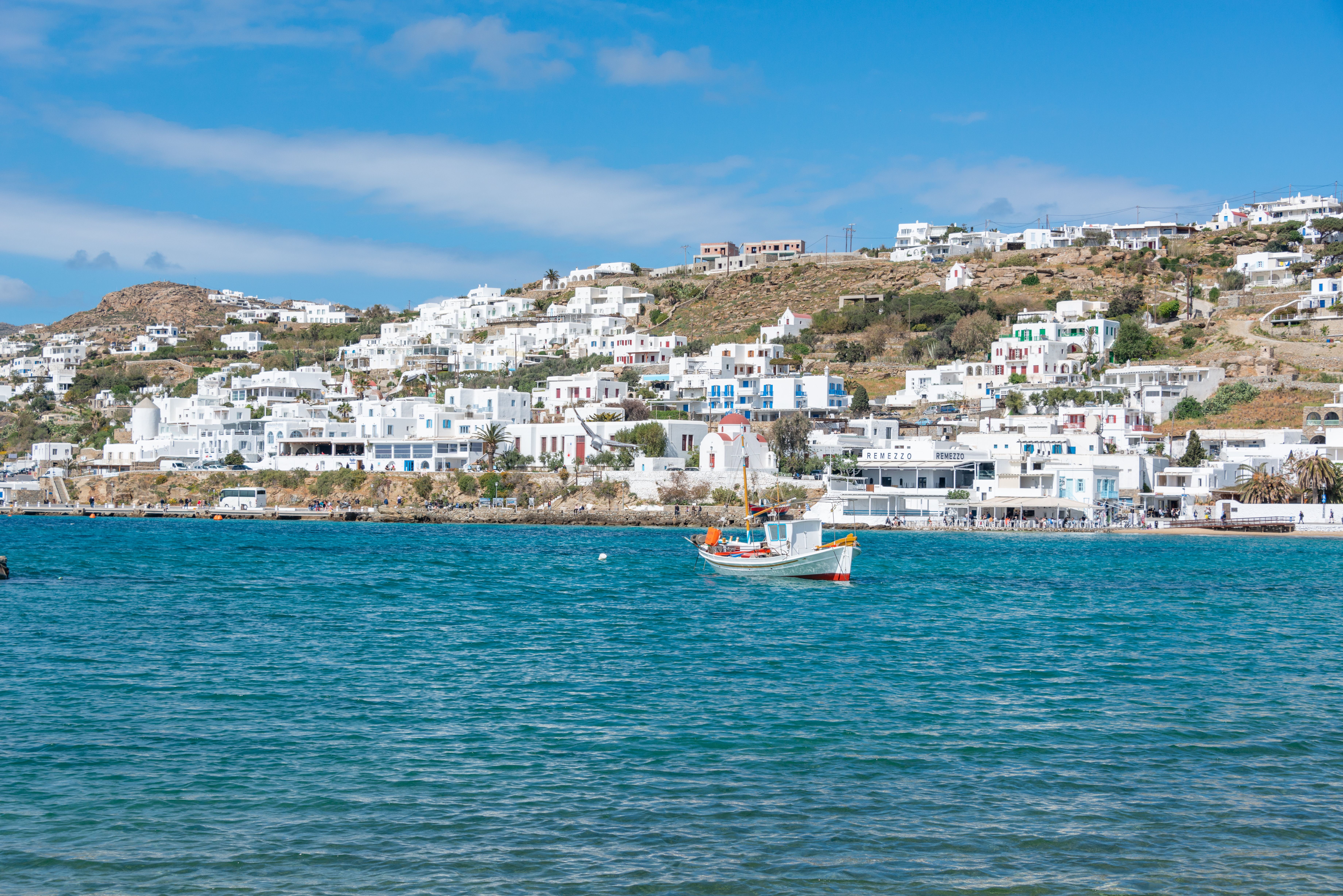 Free Scenic view of a picturesque Greek coastal town with traditional white architecture and a boat on the sea. Stock Photo
