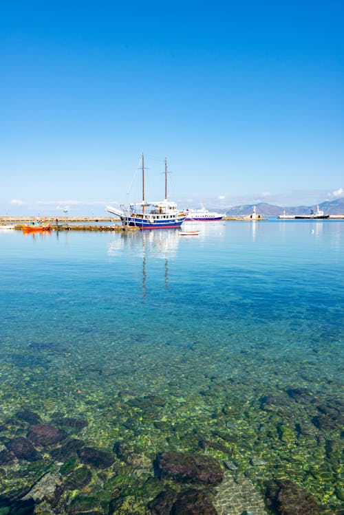 White and Blue Boat on Sea under Blue Sky