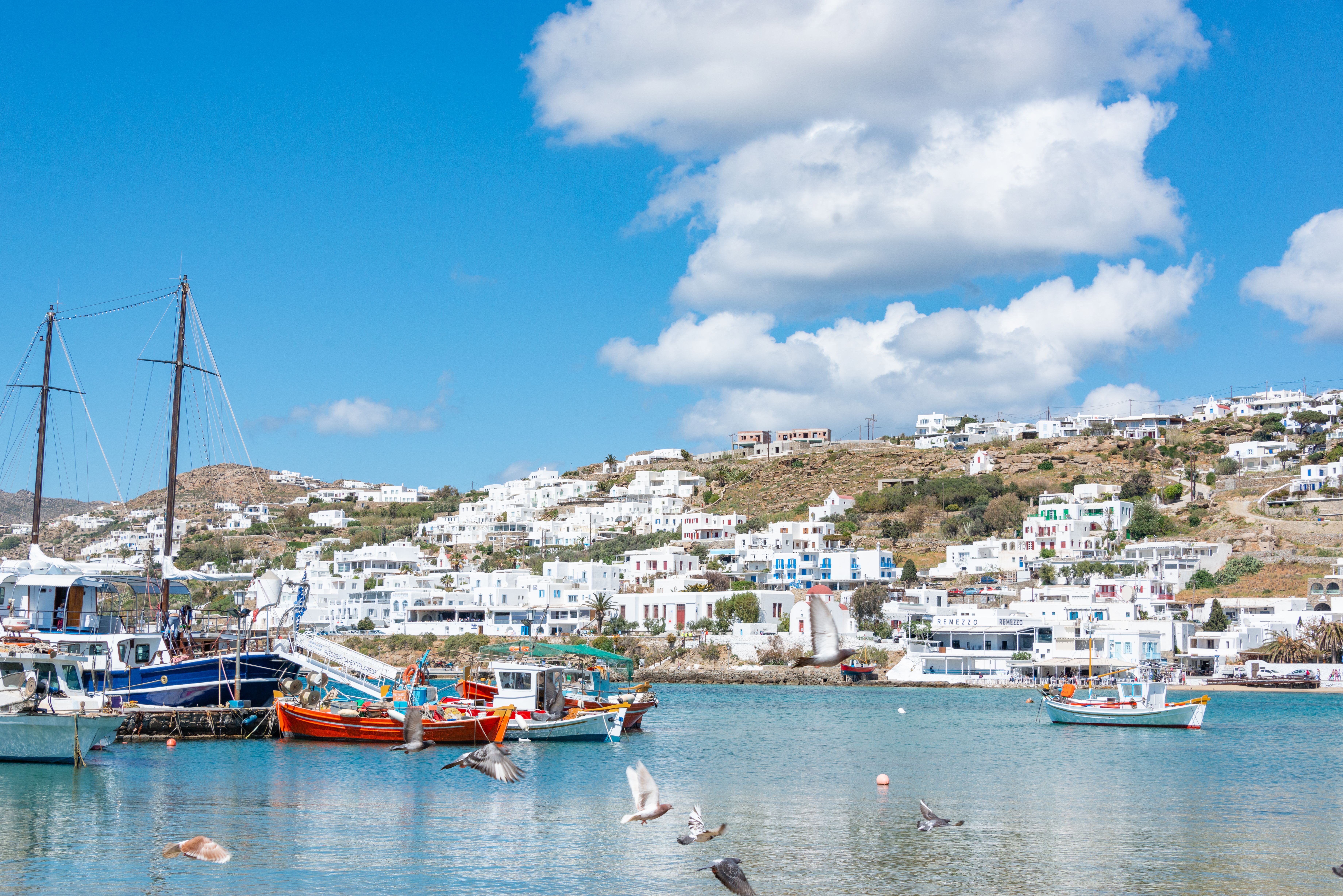 Free Beautiful Mykonos harbor view with sailboats, clear skies, and traditional architecture. Stock Photo