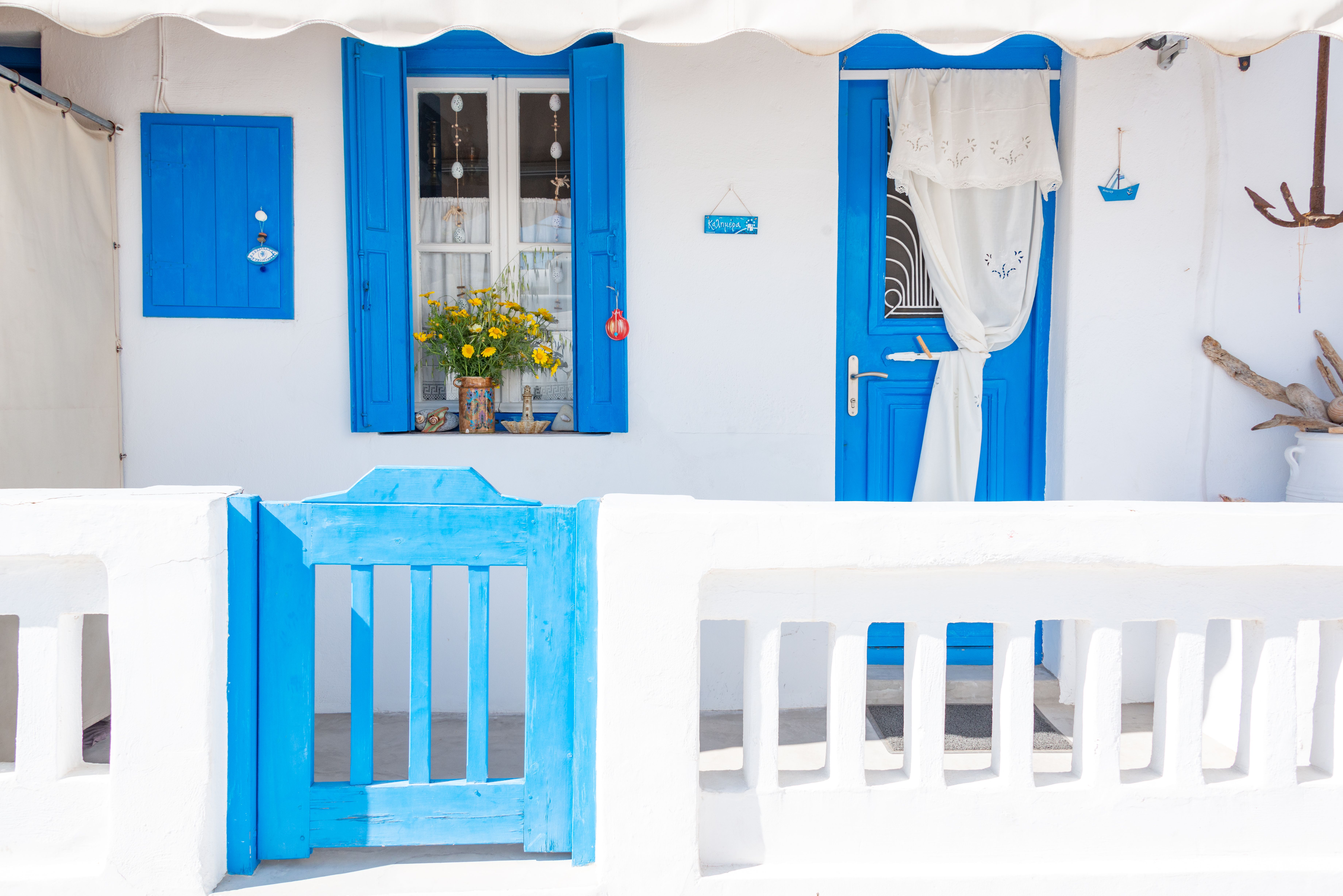 Traditional Greek home with blue shutters and doors, symbolizing Cycladic architecture style.