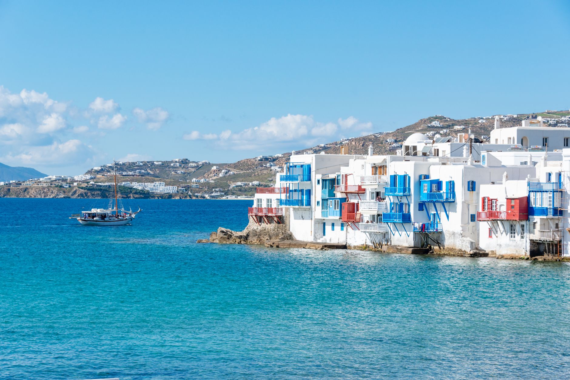 Charming white and blue houses on the Mykonos waterfront under a bright blue sky.
