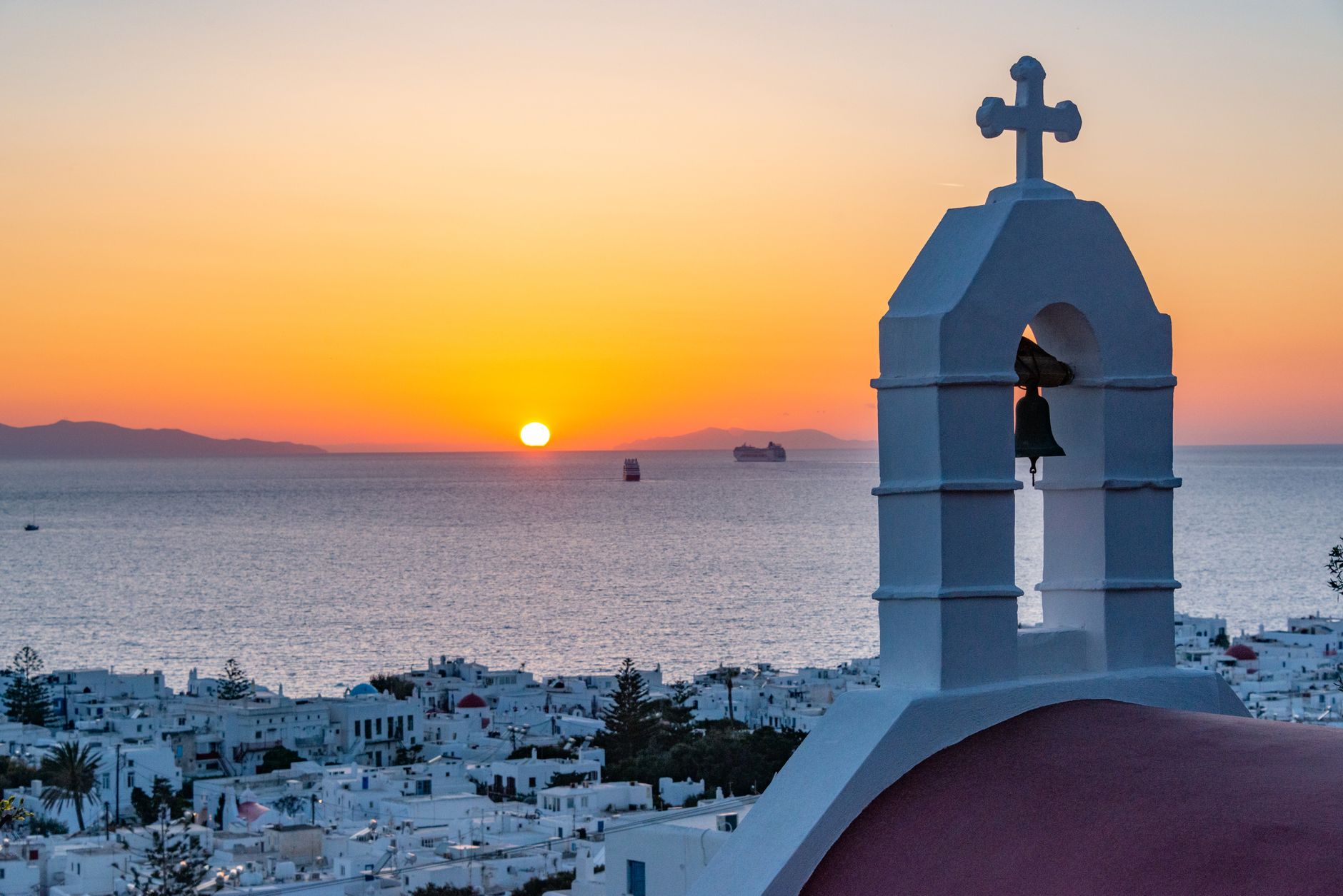 Beautiful sunset view of a traditional Greek church and the Aegean Sea in Santorini.