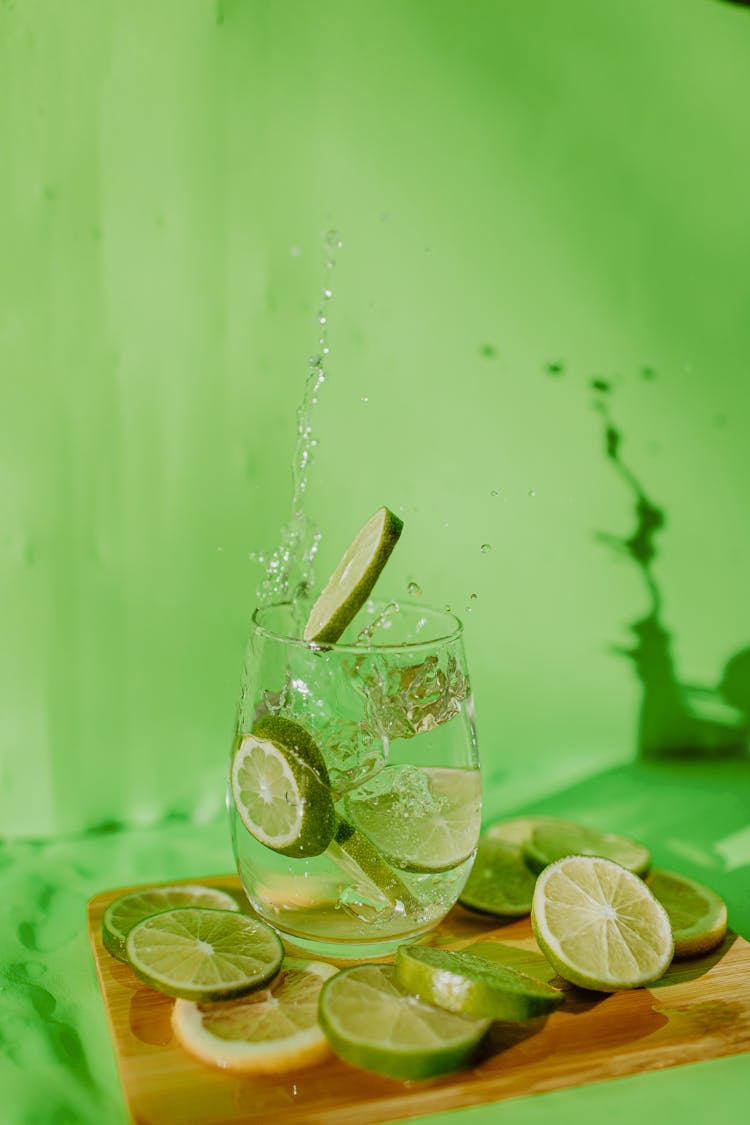 Lime Slices Falling Into Glass Of Water