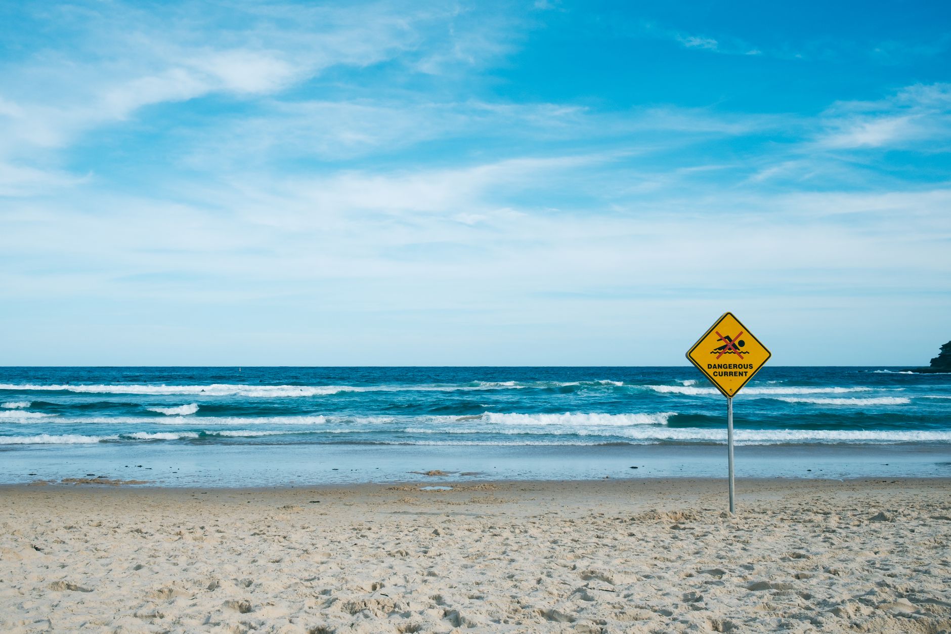 A warning sign about dangerous currents posted by the sea.