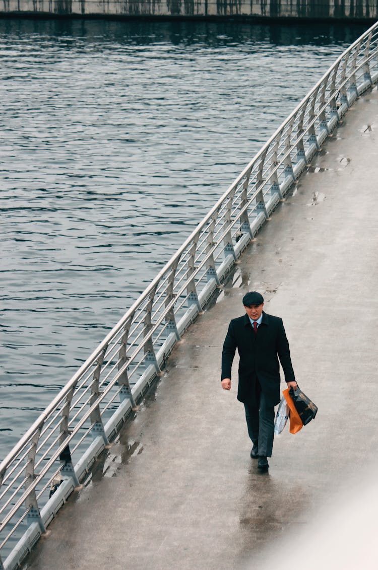 Man Walking On Bridge Near Water