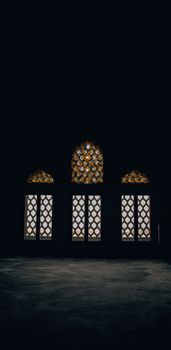 Dark interior featuring ornate windows in İstanbul, showcasing traditional Islamic design.
