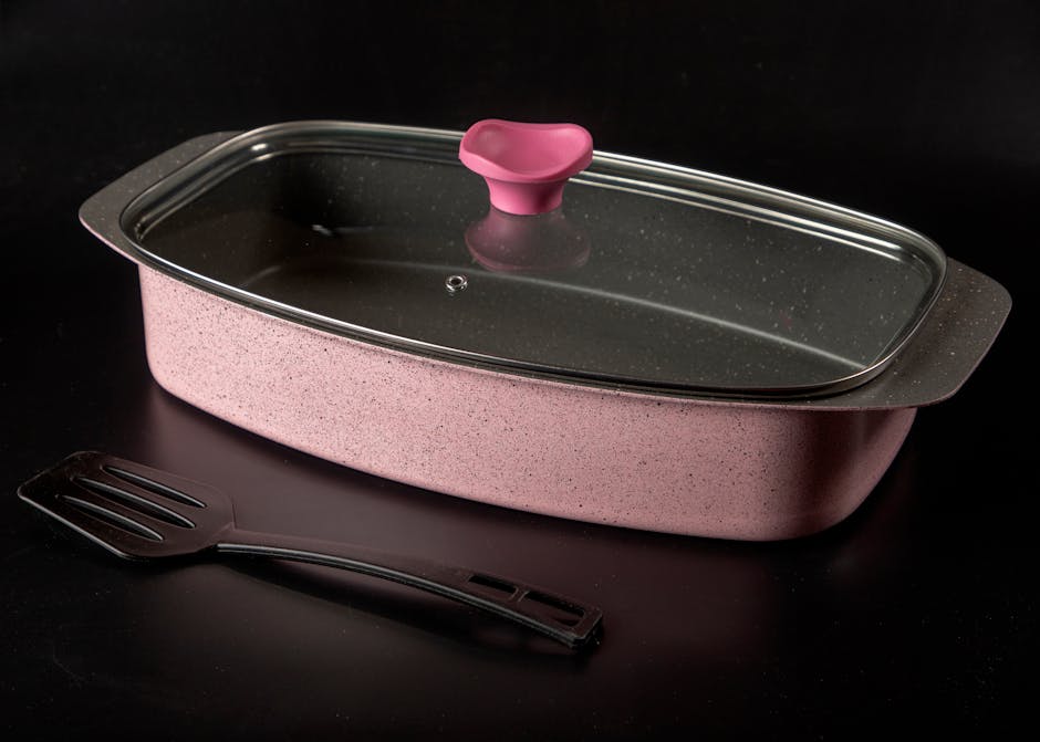 Stylish pink baking dish with glass lid and spatula, perfect for contemporary kitchens.