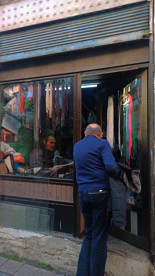 Man Talking with a Shoemaker Sitting inside the Store