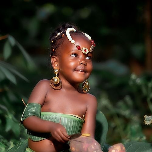 Free Charming child dressed in a leaf costume with traditional jewelry in a forest setting. Stock Photo