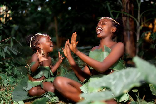 Free Mother and daughter in leaf costumes laughing and playing in a lush forest setting. Stock Photo
