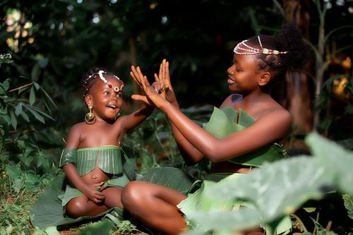 Free Mother and child playfully interacting in a lush forest setting wearing leaf costumes. Stock Photo