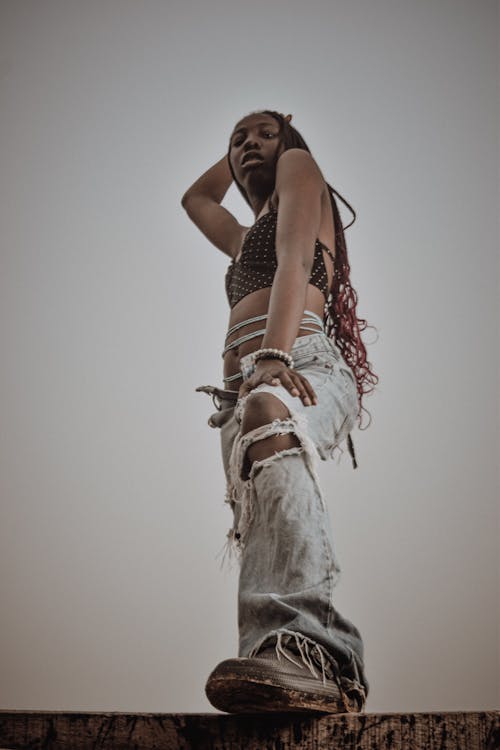 Low Angle Shot of a Young Woman in Ripped Jeans and a Crop Top Standing Outside 