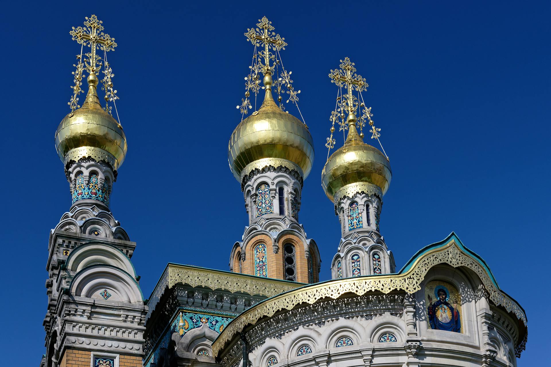 Orthodox church with golden domes and intricate designs under a clear blue sky.