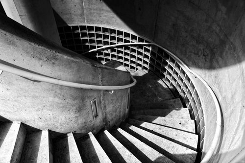 Free Captivating black and white image of a spiral concrete staircase with dramatic shadows. Stock Photo