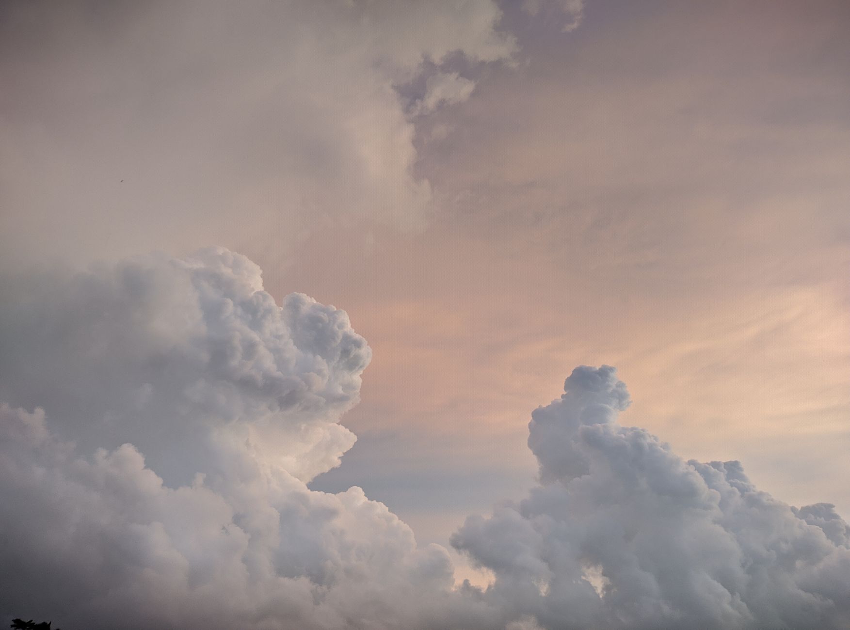 A calming view of fluffy clouds against a pastel sunset sky, perfect for relaxation themes.