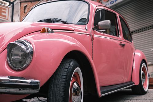 Free Charming vintage pink Volkswagen Beetle parked outdoors, showcasing classic style. Stock Photo