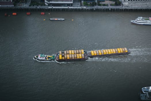 Aerial shot of a tugboat pulling cargo on the Thames River in London, England. Urban background.