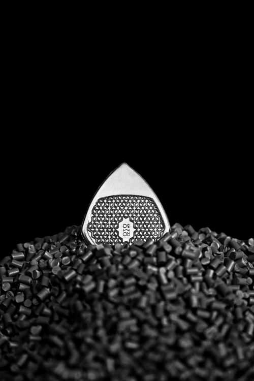 Free Black and white image of a guitar pick nestled in rubber granules, with a striking pattern. Stock Photo