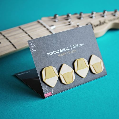 Free Showcase of honey yellow guitar picks on a turquoise background next to a guitar neck. Stock Photo