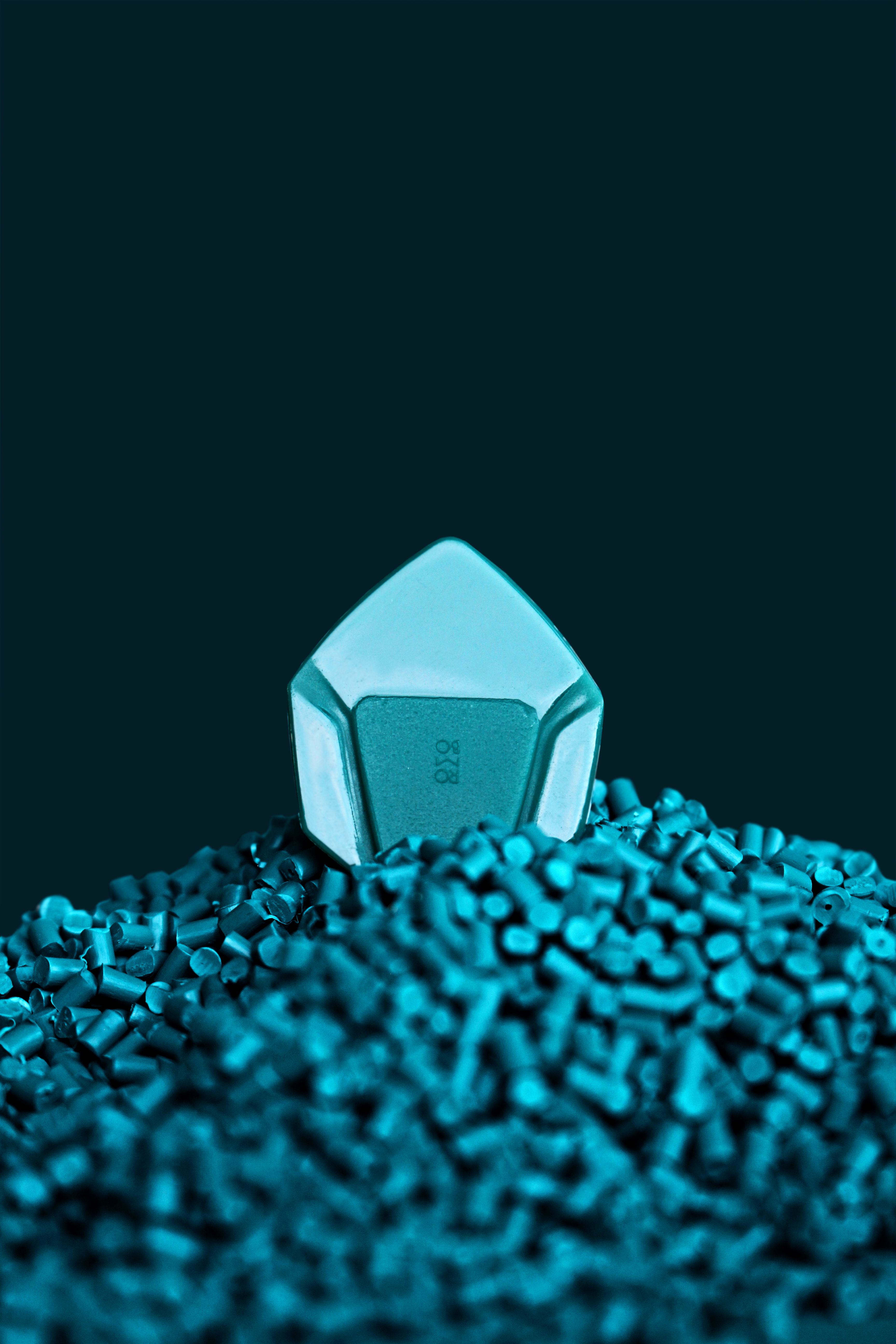 Close-up of a blue guitar pick resting atop a pile of plastic beads, studio shot.