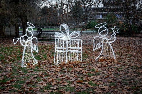 Free Illuminated angel figures and gift display in a park with fallen leaves, capturing the essence of festive winter decor. Stock Photo