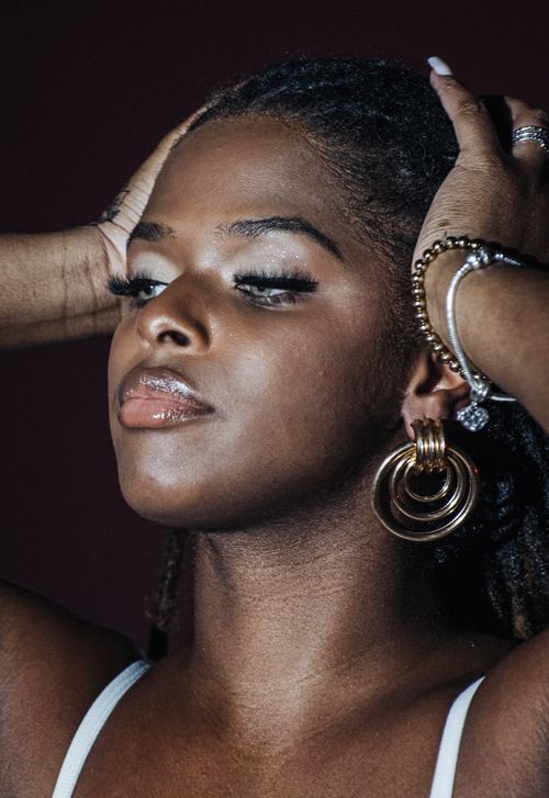 Free Close-up portrait of a stylish woman wearing bold jewelry and a confident expression, perfect for fashion and beauty concepts. Stock Photo