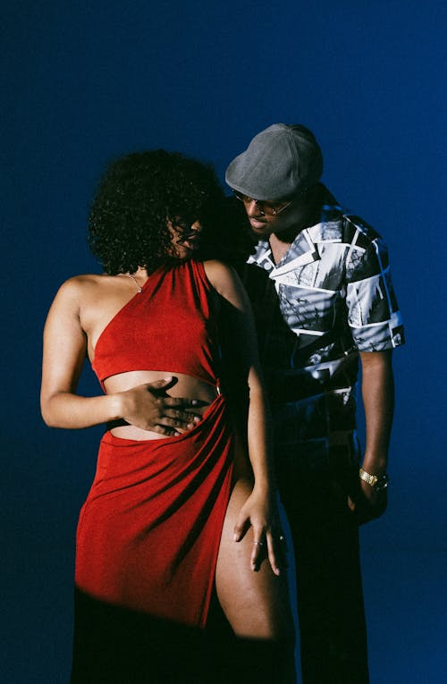 Studio Shot of a Woman in a Red Dress and Man Standing behind Her 