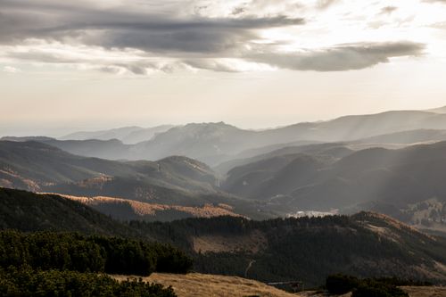 Free Breathtaking view of a mountain range bathed in morning light, with mist and dramatic clouds. Stock Photo