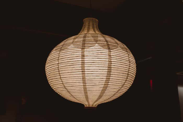 A ribbed paper pendant lamp glowing warm against a dark ceiling — photo by Vladimir Srajber on Pexels