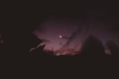 A captivating night sky featuring a crescent moon amidst silhouetted clouds.
